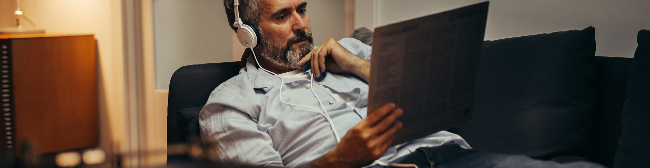 Pic showing a man reclining on a sofa listening to a vinyl album through headphones