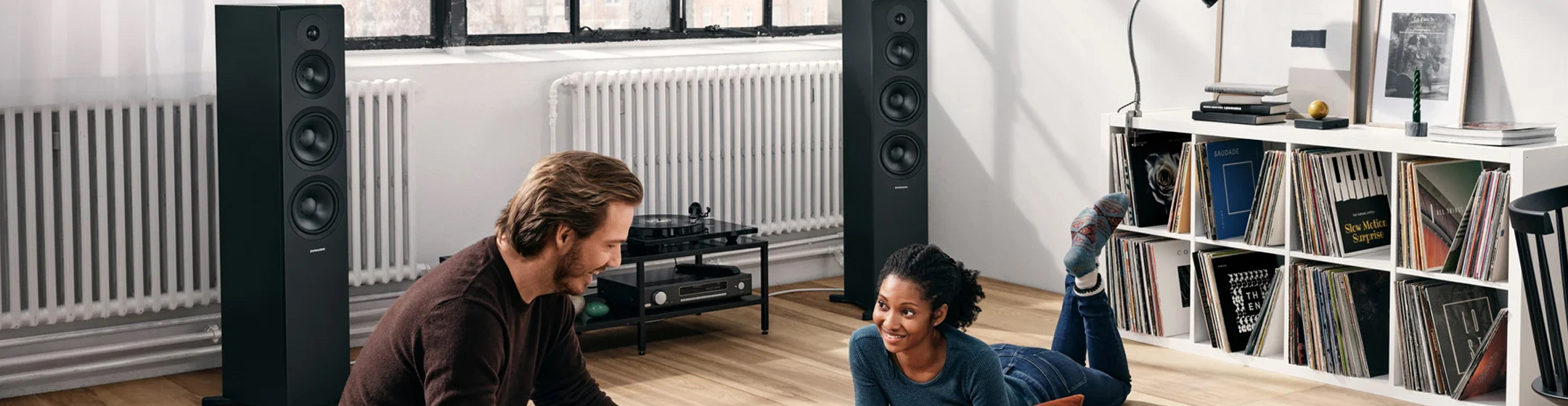 Pic showing a man and a woman listening to Dynaudio Emit speakers at home